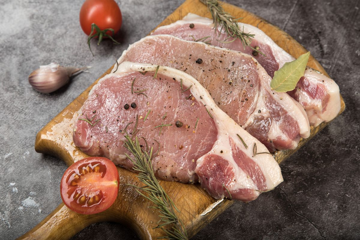 Fresh pork chops with herbs on a butcher board